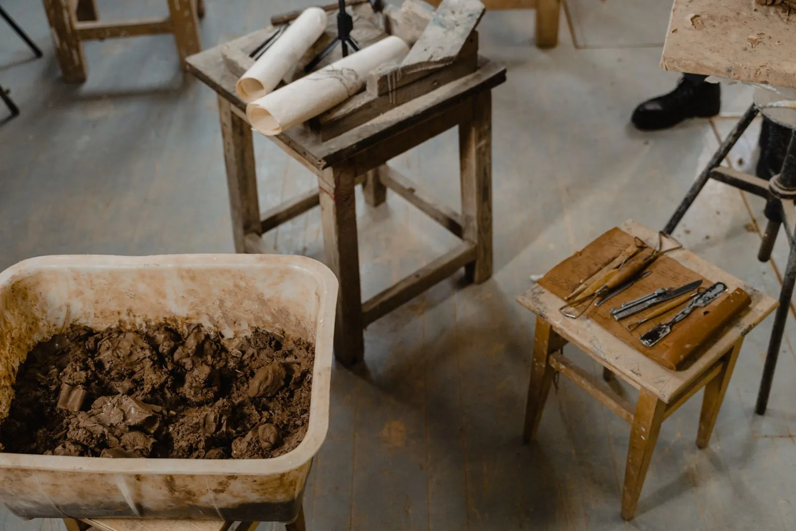 Overhead view of a craft studio with clay, tools, and wooden tables, ideal for creative projects.
